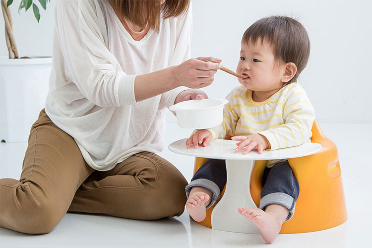 お母さんにご飯を食べさせてもらっている赤ちゃんの写真