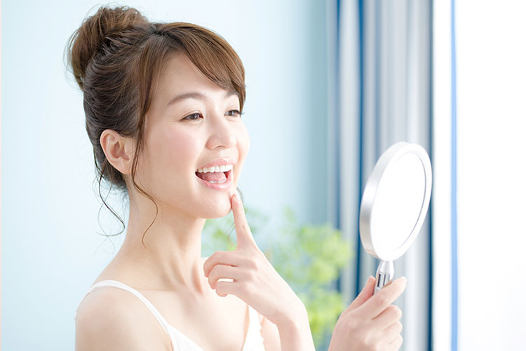 鏡で歯並びを見る女性の写真
